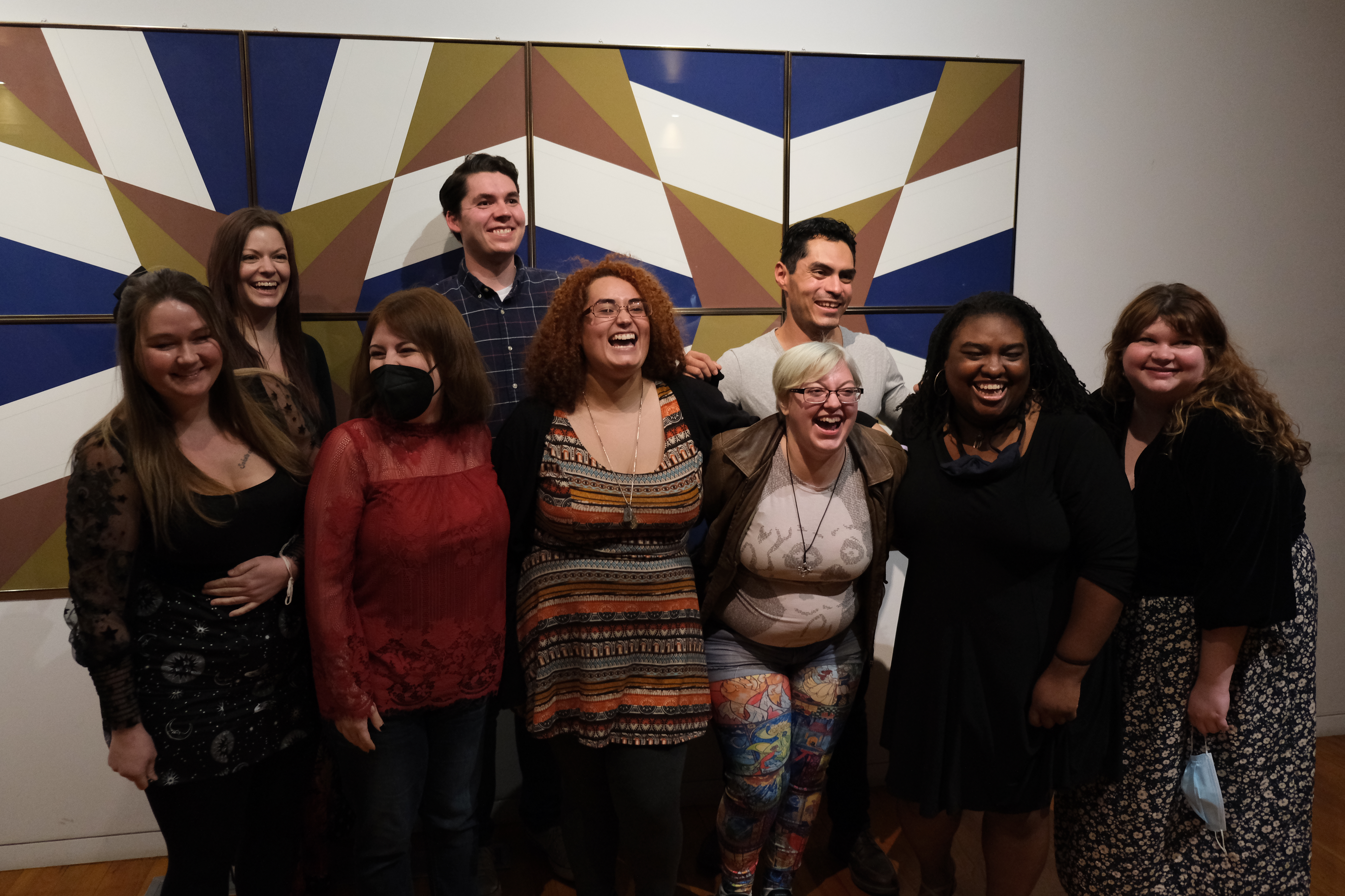 Nine MFA students standing in front of geometric art